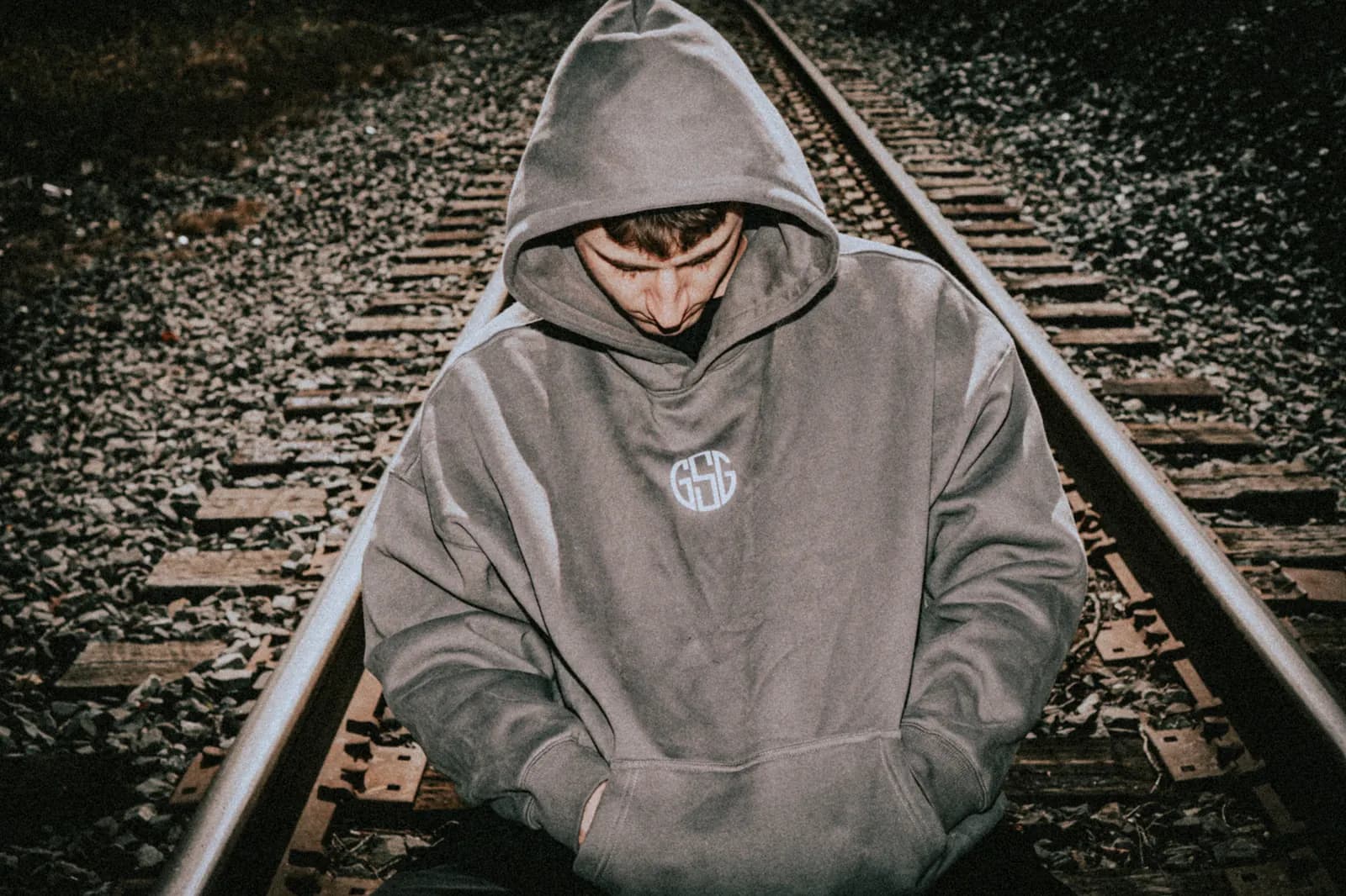The Reaper hoodie in grey, worn on the railroad tracks