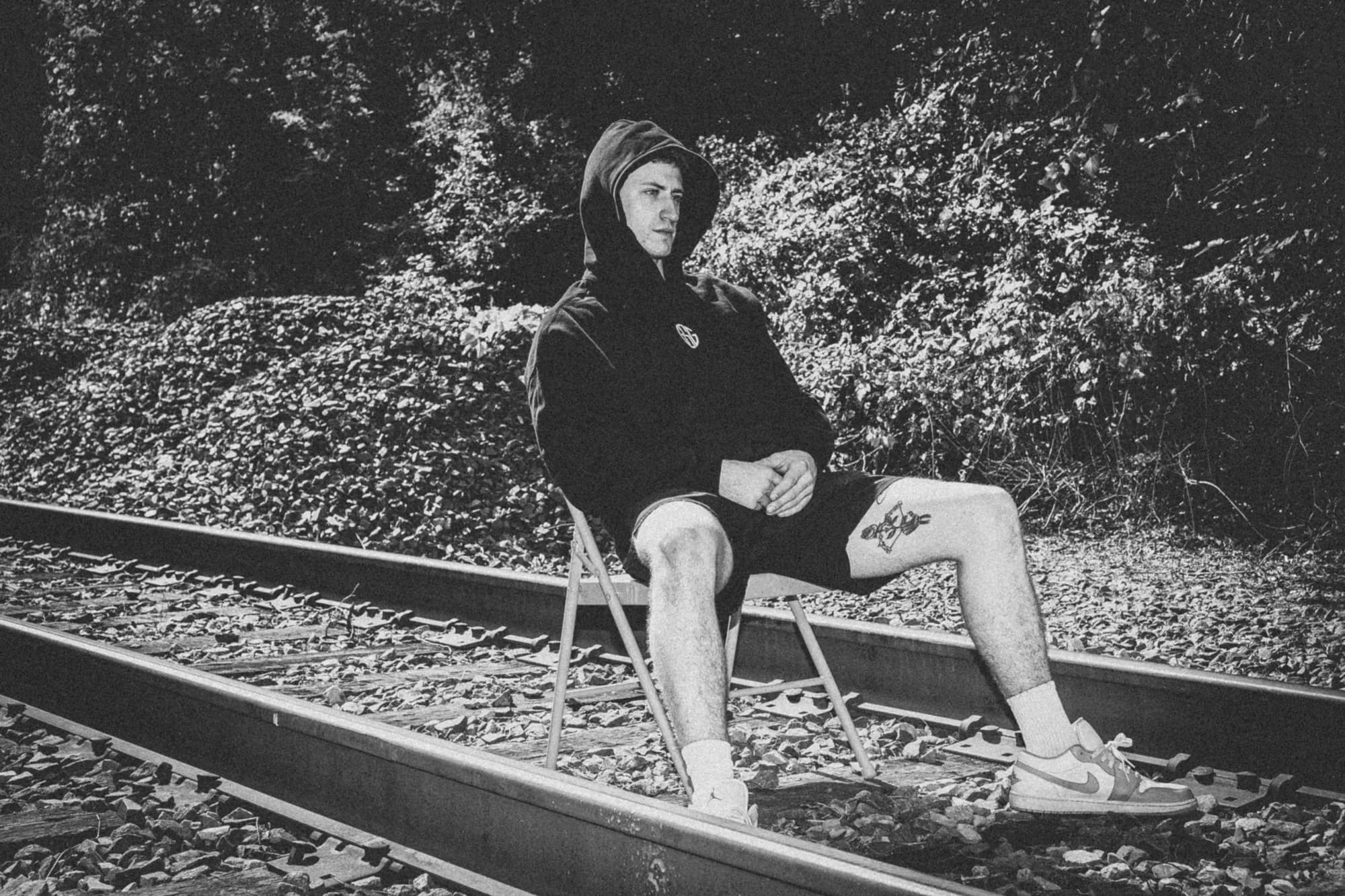 The Reaper black hoodie worn on the railroad tracks